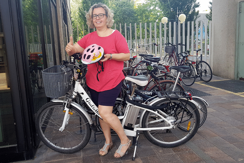 femme heureuse en vélo tenant le casque de vélo pour enfant dans sa main